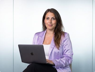 Lisa Dullnig sitzt mit einem Laptop auf den Knien vor einer hellen Wand.