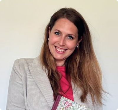 Lisa Dullnig lächelt in die Kamera, in beigem Blazer über einem pinken Oberteil.